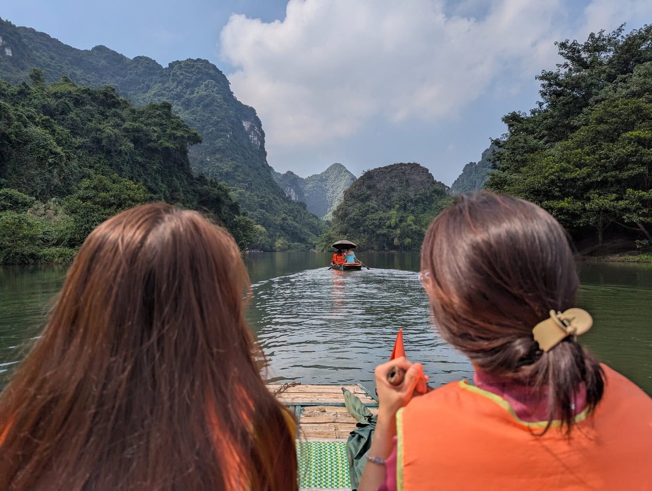 Two women sitting in a boat and enjoying rafting on river, an ecotourism tour in Vietnam