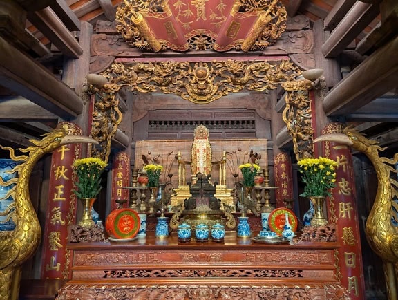 Santuario con estatuas de oro y flores dentro del templo de la pagoda, un sitio turístico y de la UNESCO en Vietnam