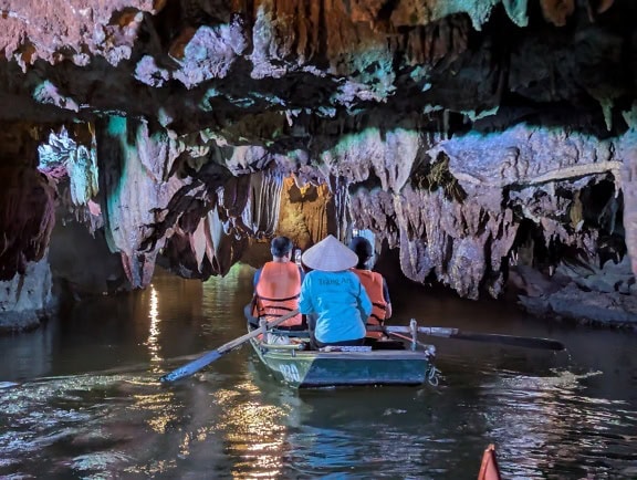 Turister som utforsker en hule i en båt på en underjordisk elv, en øko-turistattraksjon i et Vietnam