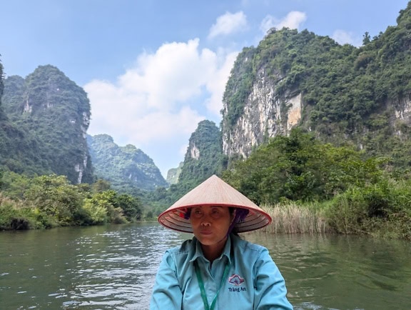 Femme vietnamienne dans un bateau avec un chapeau conique asiatique traditionnel appelé non la sur la tête