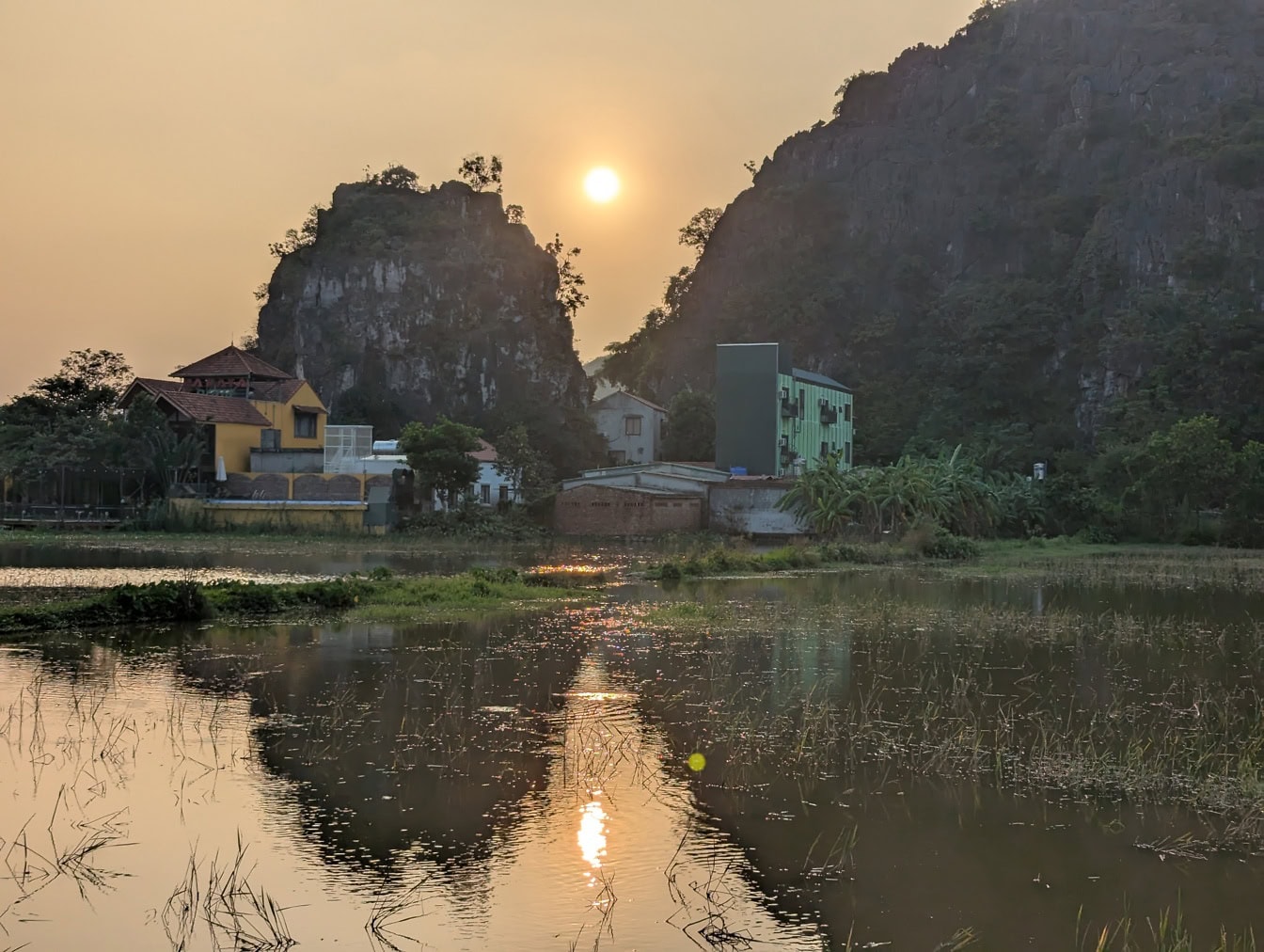 Západ slunce v severním Vietnamu nad bažinou obklopující venkovské osídlení