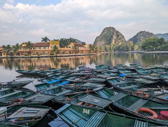 Panoraama järven rannalla pienillä veneillä telakoituna Emeraldan lomakohteeseen Tam Coc Trang Anissa lähellä Ninh Binhin kaupunkia, joka on Unescon perintökohde Vietnamissa