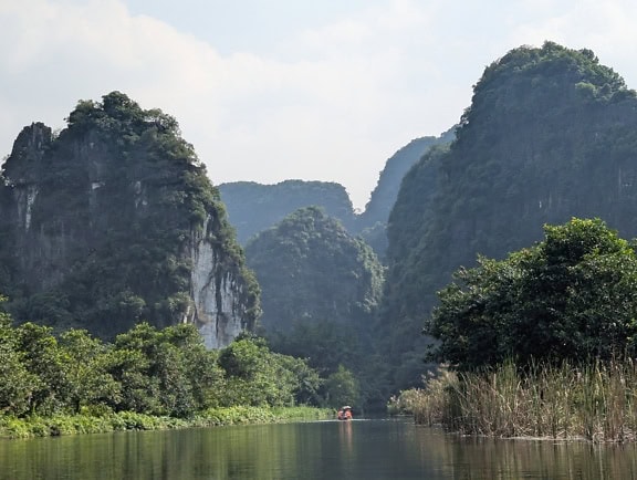 The Ninh Binh river in valley with trees and mountains, northern Vietnam