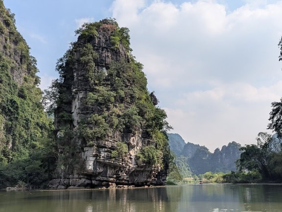 Gran acantilado sobre el río con árboles que crecen en él, Trang An cerca de Ninh Binh, Vietnam