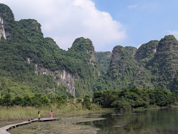 A mocsárban fából készült ösvényen álló turisták, ökoturisztikai túra Vietnam vadonjában