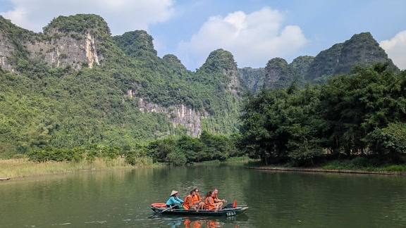 Personas con chalecos salvavidas mientras hacen rafting en un bote en un río, ecoturismo en el norte de Vietnam, sudeste asiático