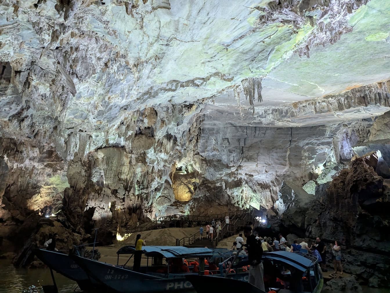 A group of tourists on the riverbank of an underground river in a cave