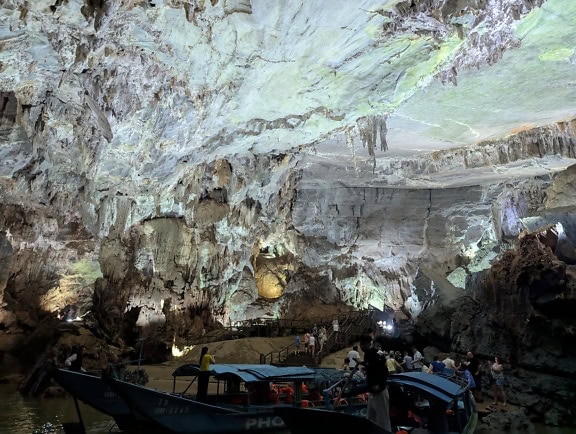 En grupp turister på flodstranden av en underjordisk flod i en grotta