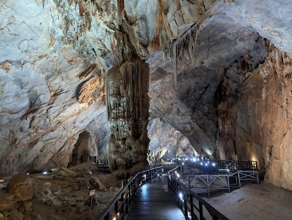 Gångväg i en grotta runt naturlig pelare gjord av stalaktit och stalagmit