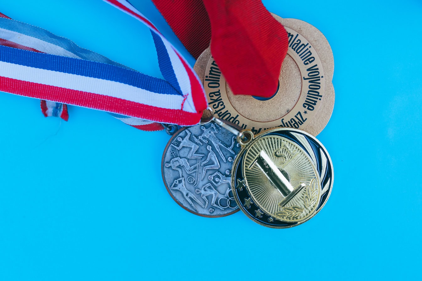 Sports medals on a blue background, a gold medal with the number one imprinted with a silver and bronze medal, an award for achievements in sports