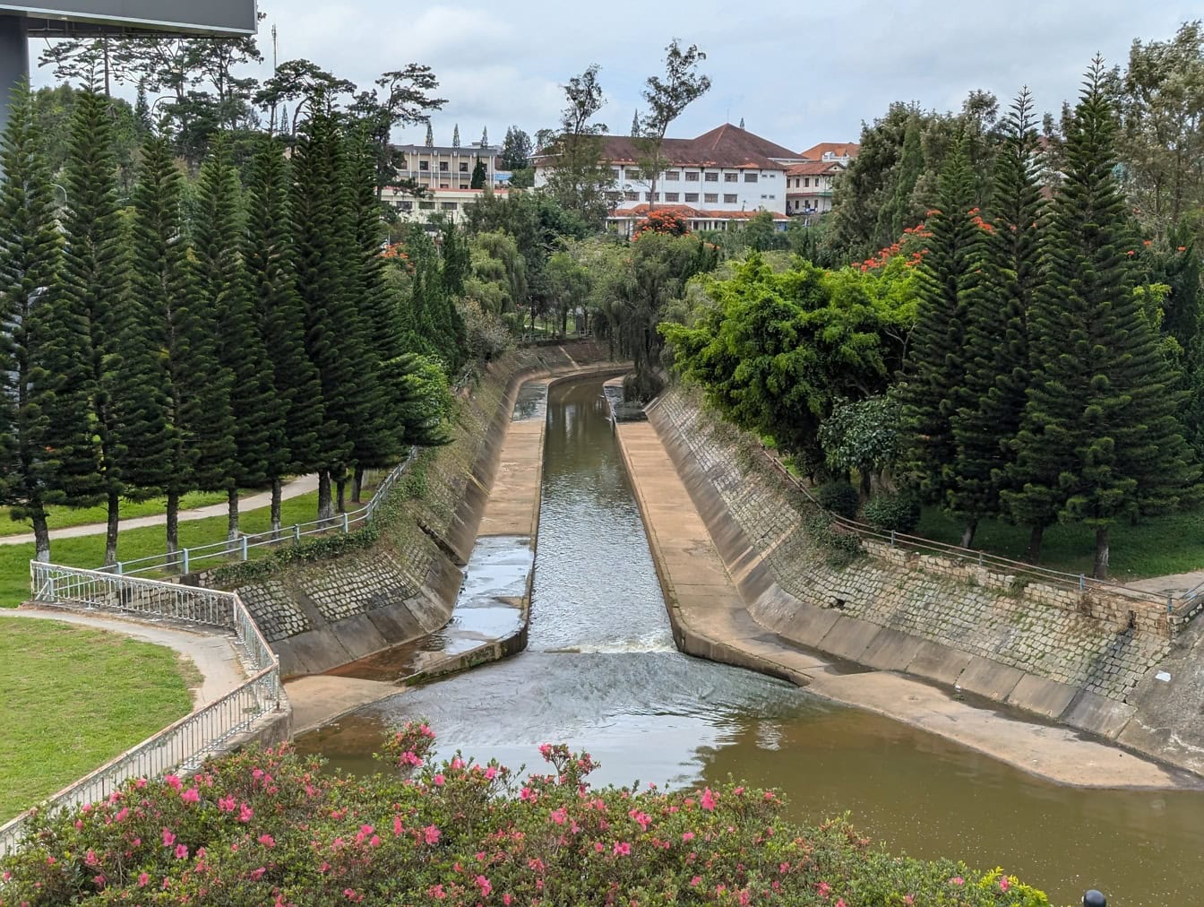 Taman kota dengan saluran air dengan pepohonan dan bangunan di latar belakang, Dalat, vietnam