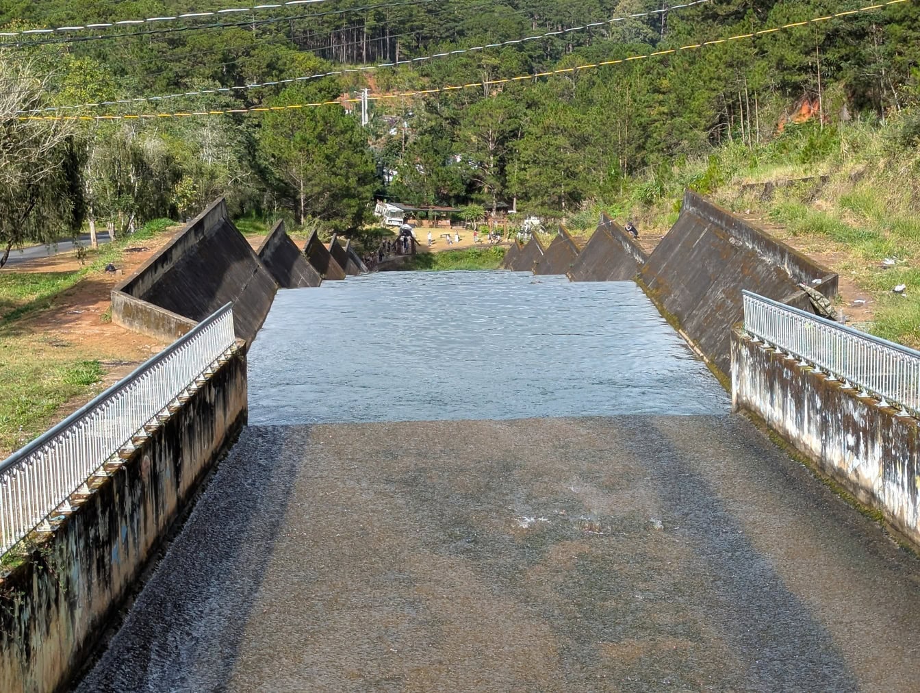 Ein Flusswasser in einem engen Betonkanal, eine Brücke aus Damm