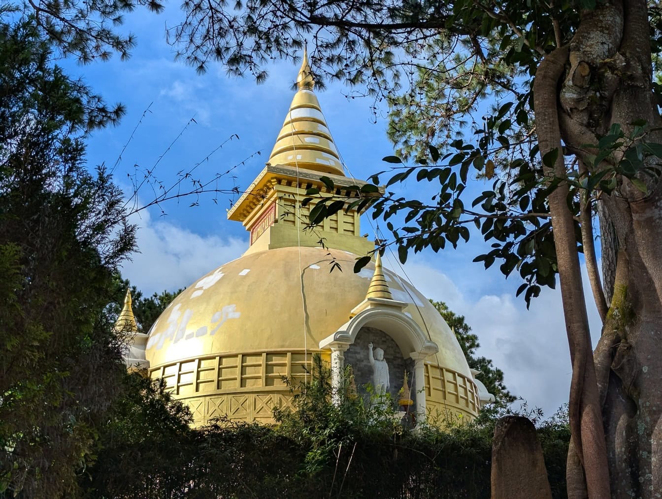 Edificio dorato con una statua in cima a una cupola, il Truc Lam un monastero buddista, città di Da Lat o Dalat, Vietnam