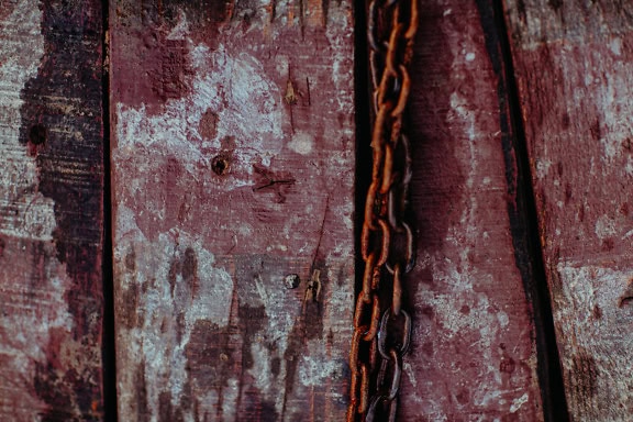 Rusty old iron chain on a wooden surface, a detailed texture of dirty planks