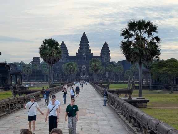 turisti che camminano su una passerella di pietra nel parco con il famoso antico tempio di Angkor Vat sullo sfondo, Cambogia