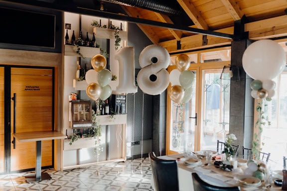 Un ballon gonflé à l’hélium dans une pièce chic avec une table et des chaises pour une fête d’anniversaire