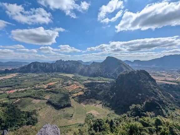 Panorámás táj hegyekkel, dombokkal és vidéki mezőgazdasági területekkel a völgyben Vang Vieng város közelében, Laosz vidéki tartományában