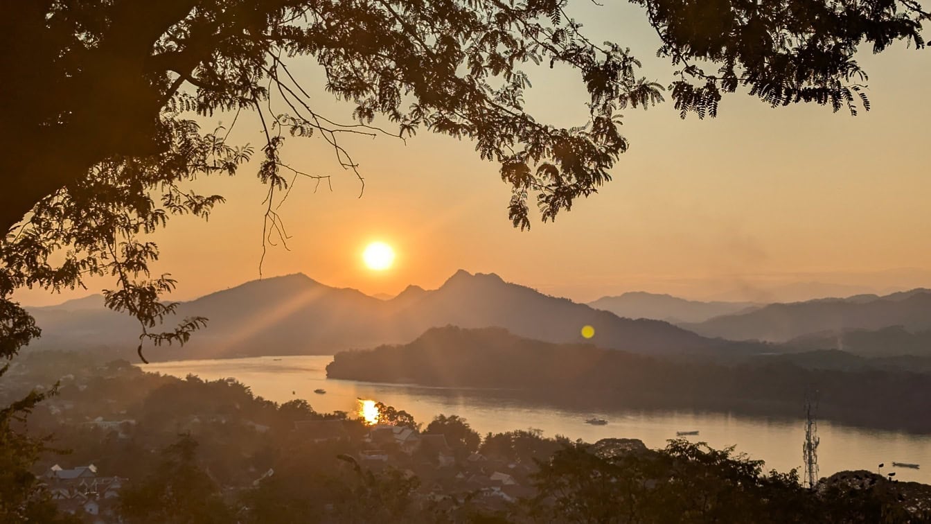 Helles Sonnenlicht kurz vor Sonnenuntergang über dem Nam Khan Fluss, eine dämmrige Landschaft über dem Luang Prabang, Laos