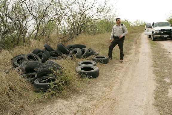 law, enforcement, officer, inspects, tires, illegally, dumped
