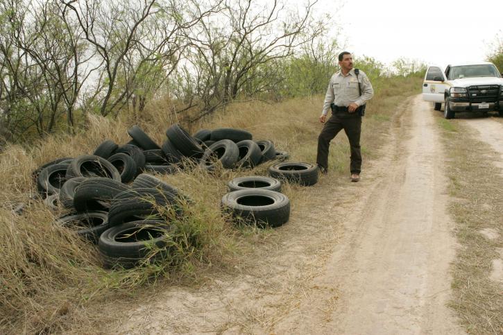 law, enforcement, officer, inspects, tires, illegally, dumped