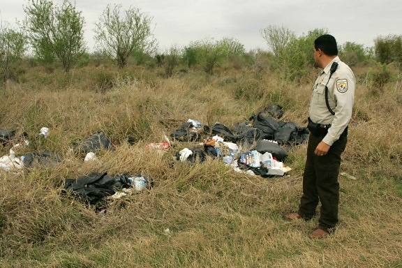 law, enforcement, officer, inspects, trash, illegally, dumped