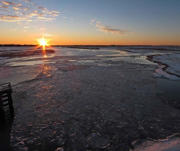 Sunrise sunlight melting frozen water on lake