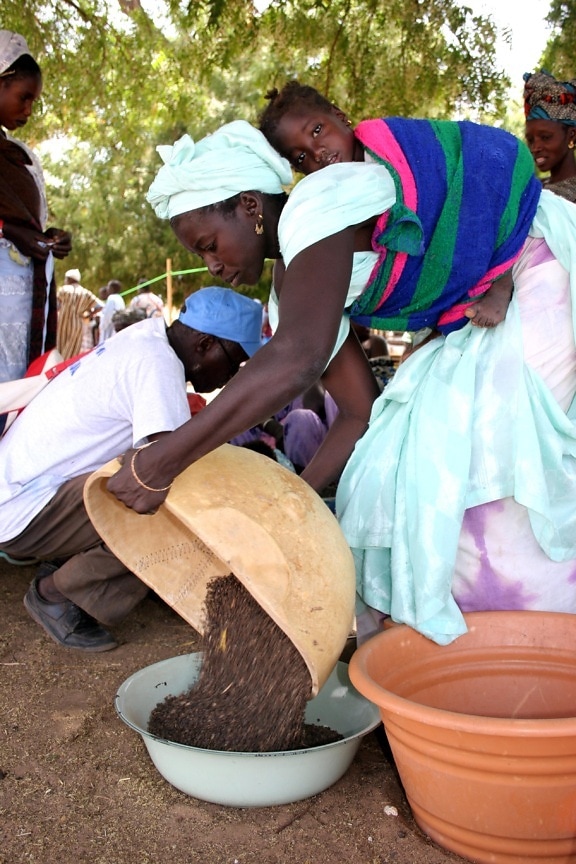 at-a-fair-in-touba-toul-a-senegalese-merchant-with-her-infant-strapped-to-her-back-exchanges-her-produce-550x825.jpg