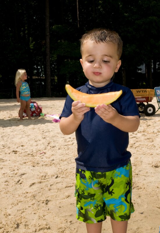 boy, holding, slice, cantaloupe, hands, standing, beach, sand