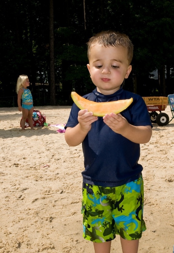 хлопчик, проведення, скибочка, дині, руки, стоячи, пляж, пісок
