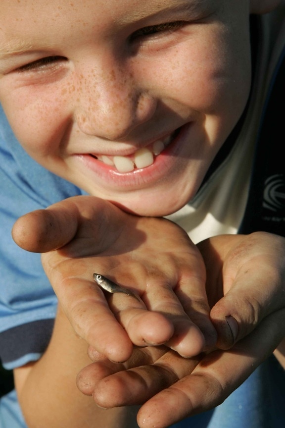 up-close, face, young boy, holds, small, fish, hand