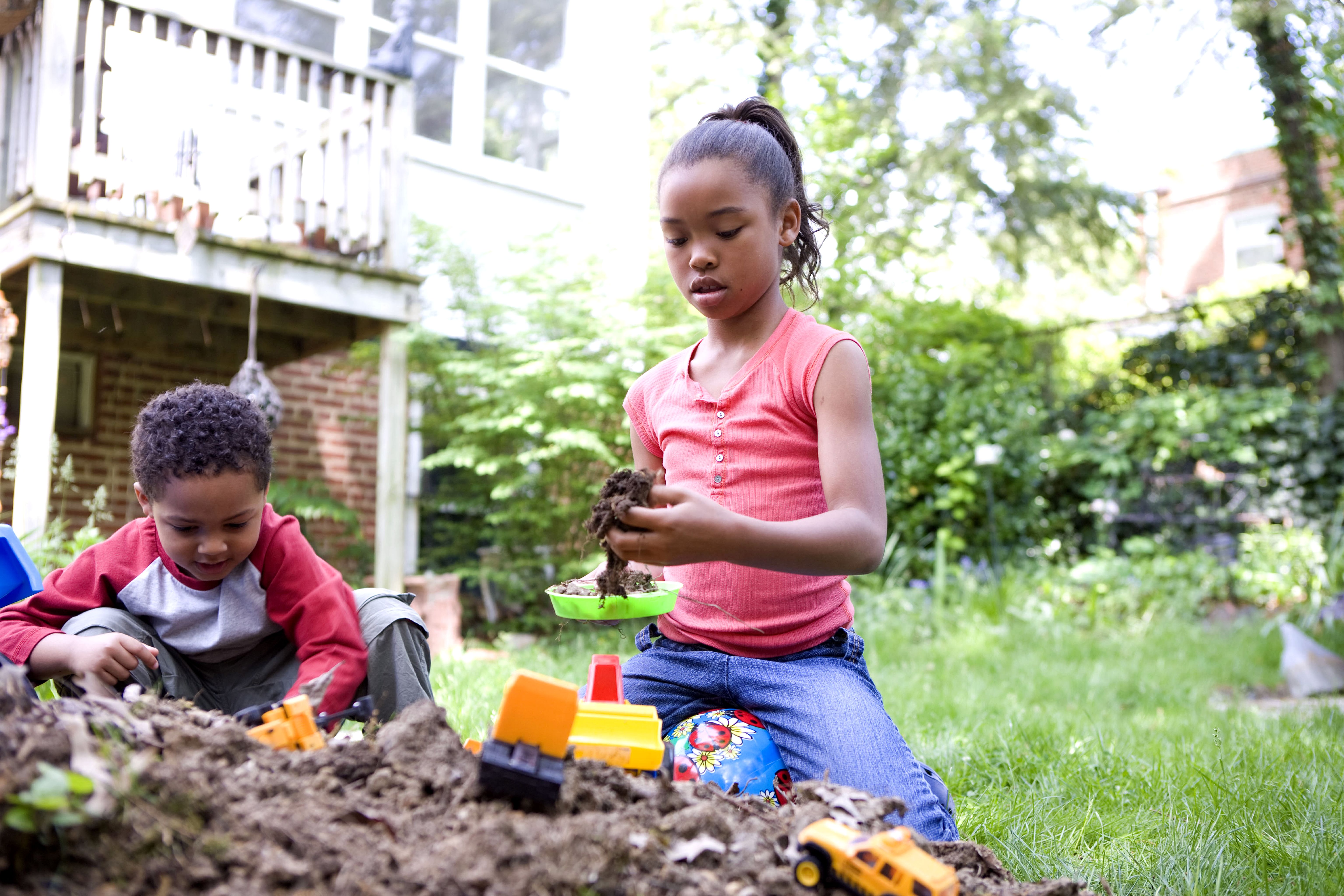 two young african american children were playing outside in a backyard dirt pile
