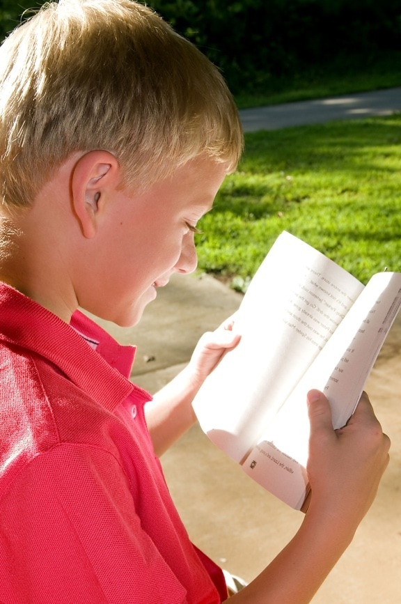 young boy, photographed, reading, book, outdoors, setting