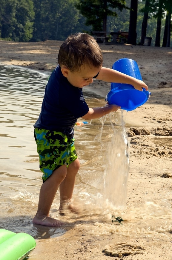 mladý chlapec, ktorý drží, vody, plnené, hračky, vedierko