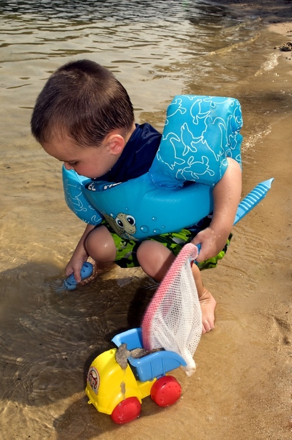 молодой мальчик, на коленях, пляж, холдинг, игрушка, ажурные, рука, пластик, сито, слева