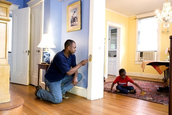 father, repairing, interior, door, frame, young son, play, toy, car, adjacent, room