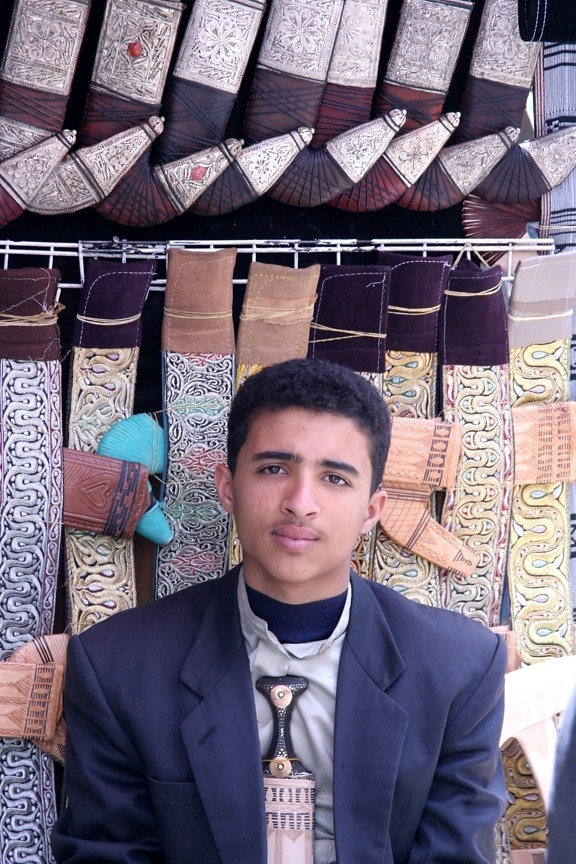 young man, earns, income, selling, traditional, Yemen, knives, open, market