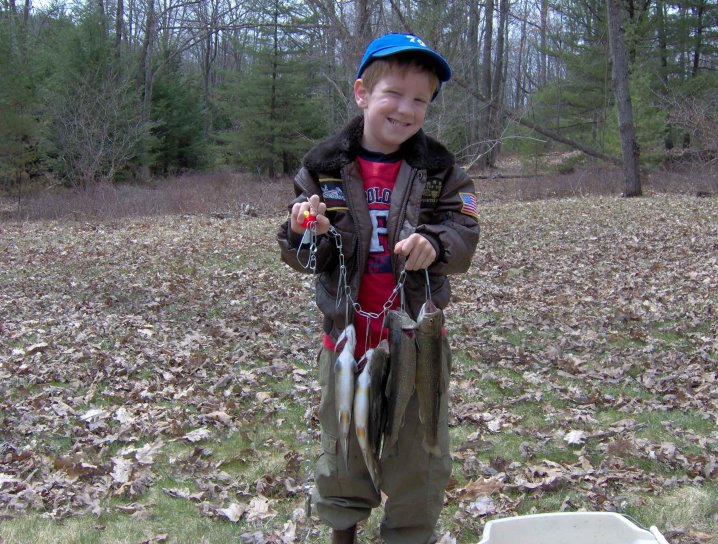 Pesca del muchacho, sosteniendo pescados cogidos